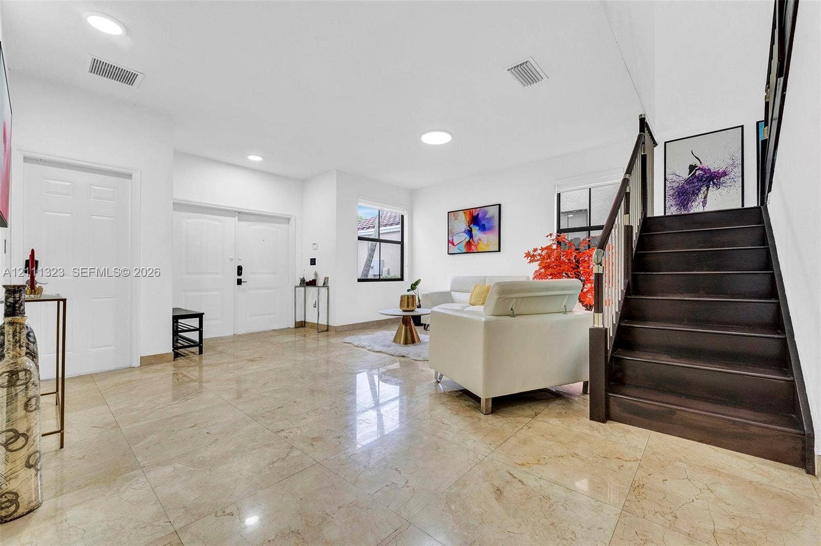 Entryway featuring polished stone flooring, recessed lighting, and a staircase with dark wood treads and metal railing