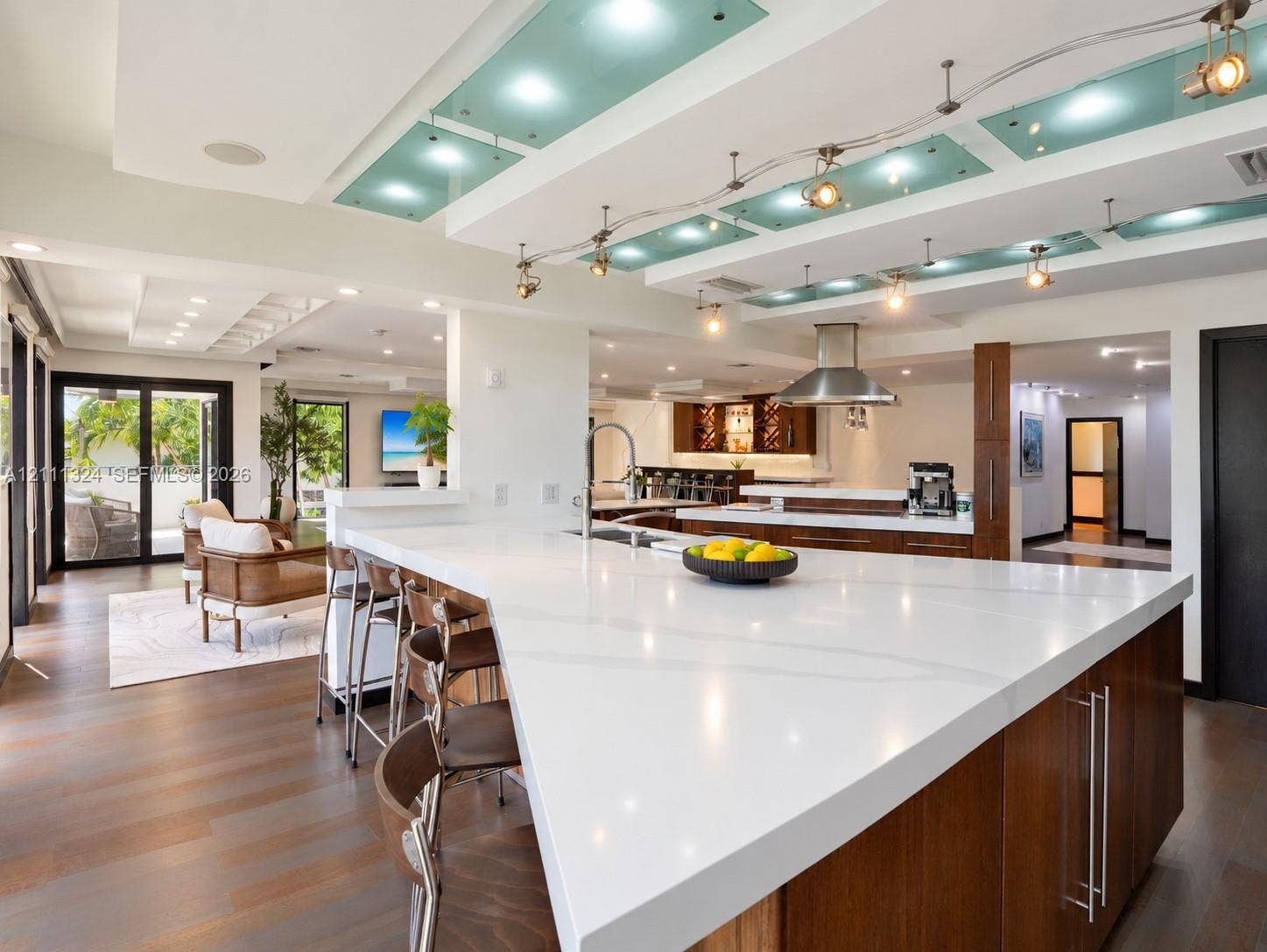Kitchen featuring an oversized island with a solid surface countertop, wood-finish cabinetry, stainless steel range hood, recessed ceiling lighting with frosted glass panels, and wood-finish flooring