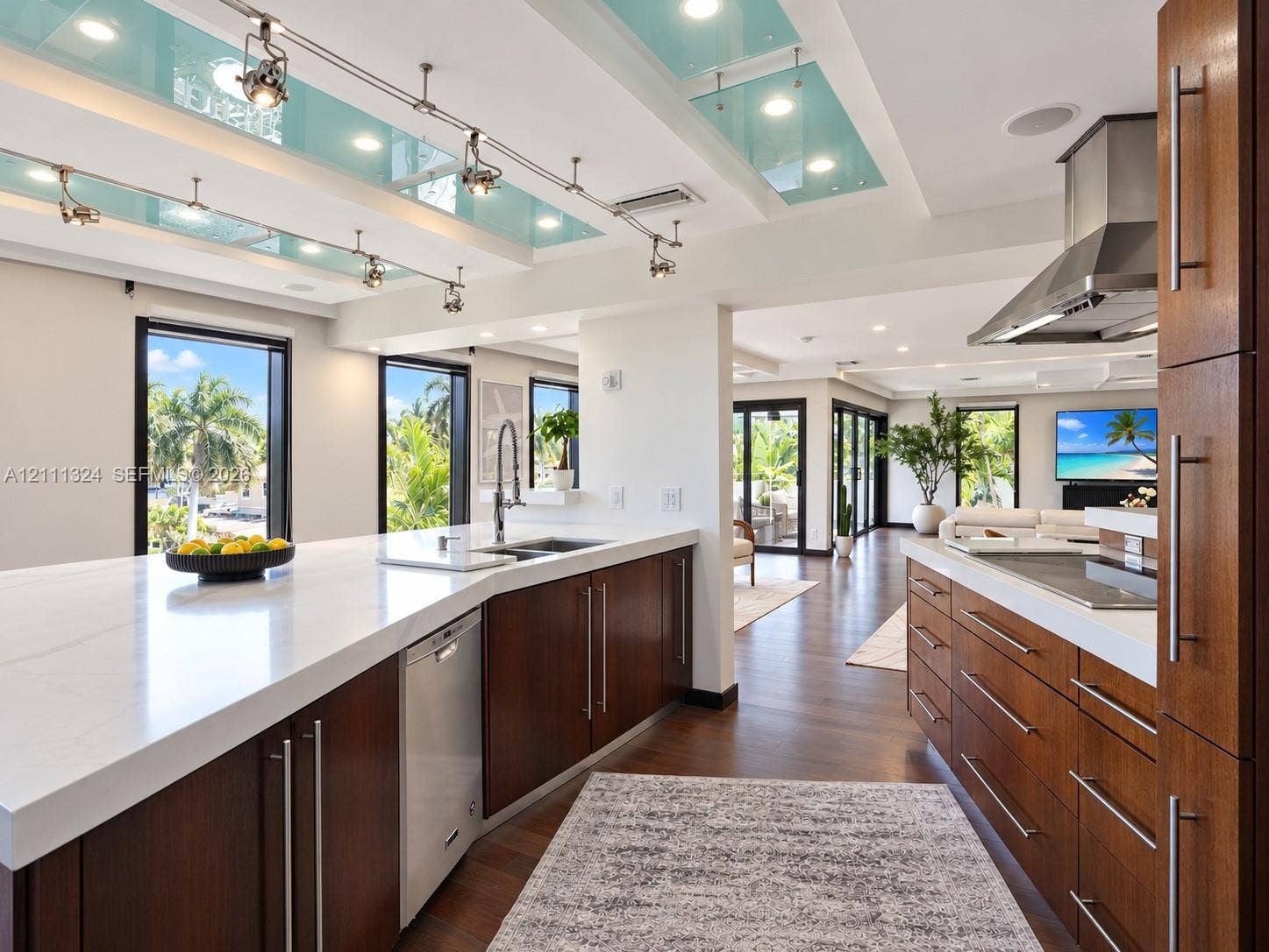 Modern kitchen featuring custom wood cabinetry, quartz countertops, a stainless steel range hood, track lighting, and recessed ceiling accents