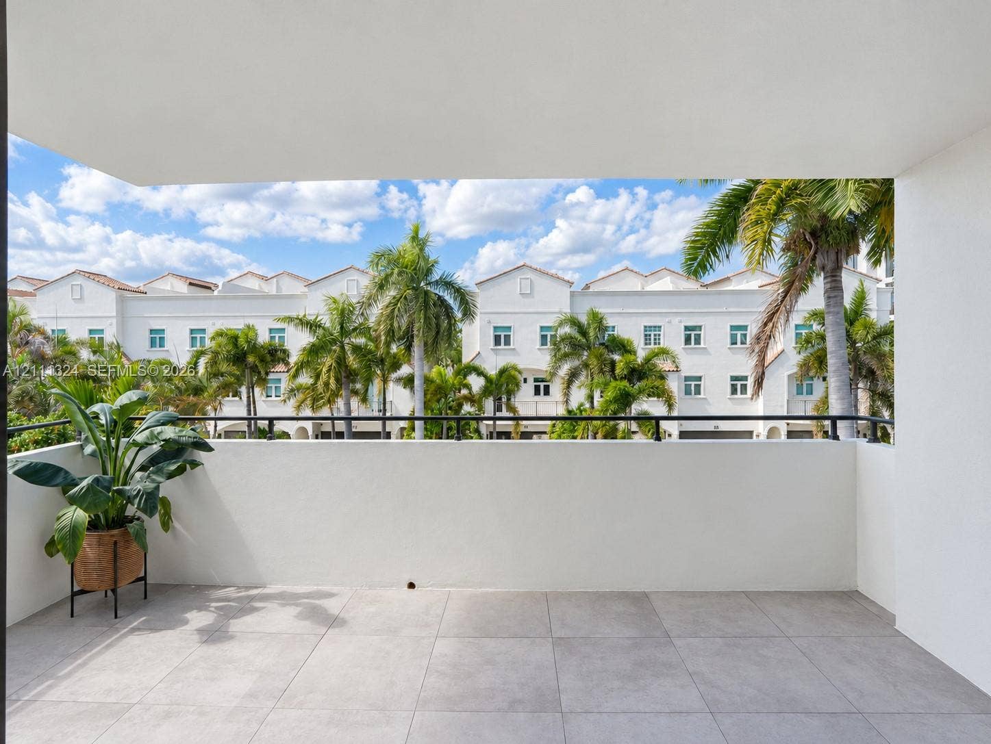 Covered balcony featuring large-format stone-finish floor tiles and a black metal railing