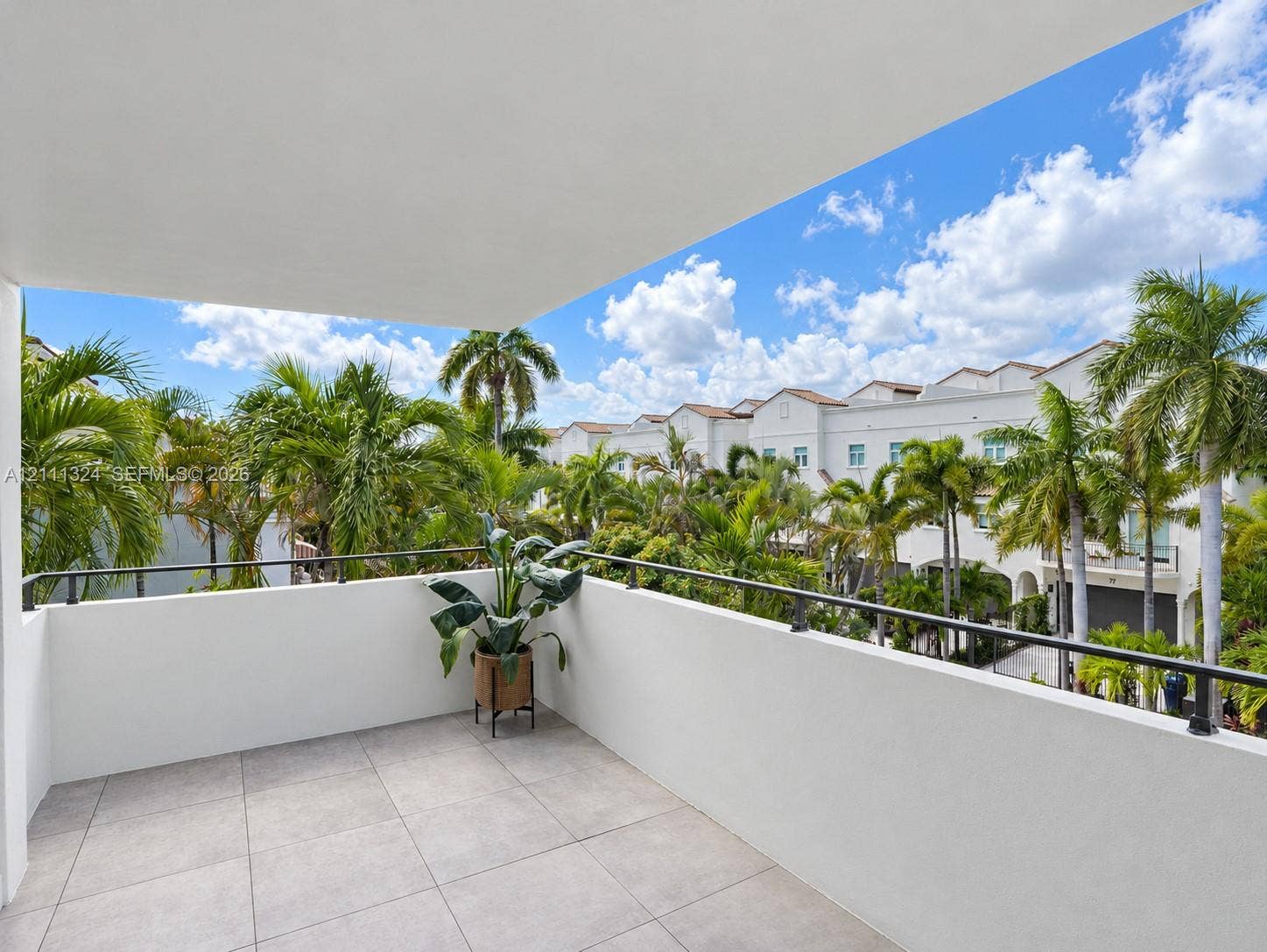 Covered balcony featuring neutral stone-finish tile flooring and a black metal railing