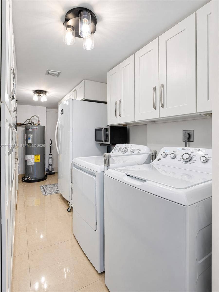 Laundry area featuring white shaker-style wall cabinets with brushed nickel hardware, polished tile flooring, and multi-light flush-mount ceiling fixtures