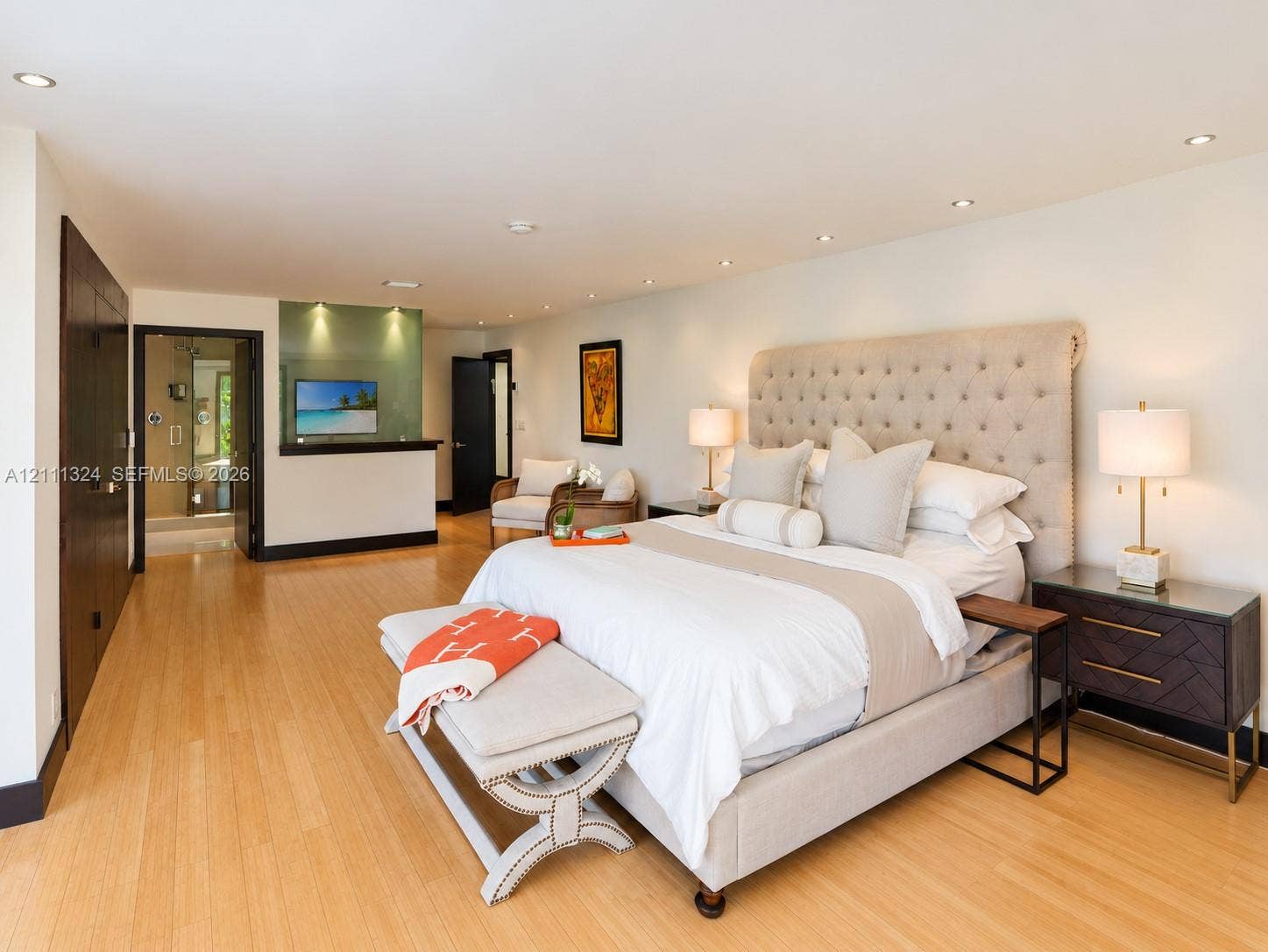 Spacious room featuring light wood-finish flooring, recessed ceiling lighting, and a frosted glass partition wall