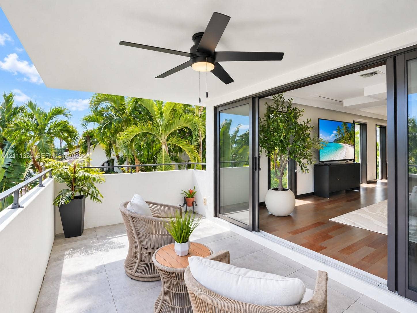 Covered balcony featuring large-format stone tile flooring, a matte black ceiling fan with integrated lighting, and a metal-rail balcony perimeter