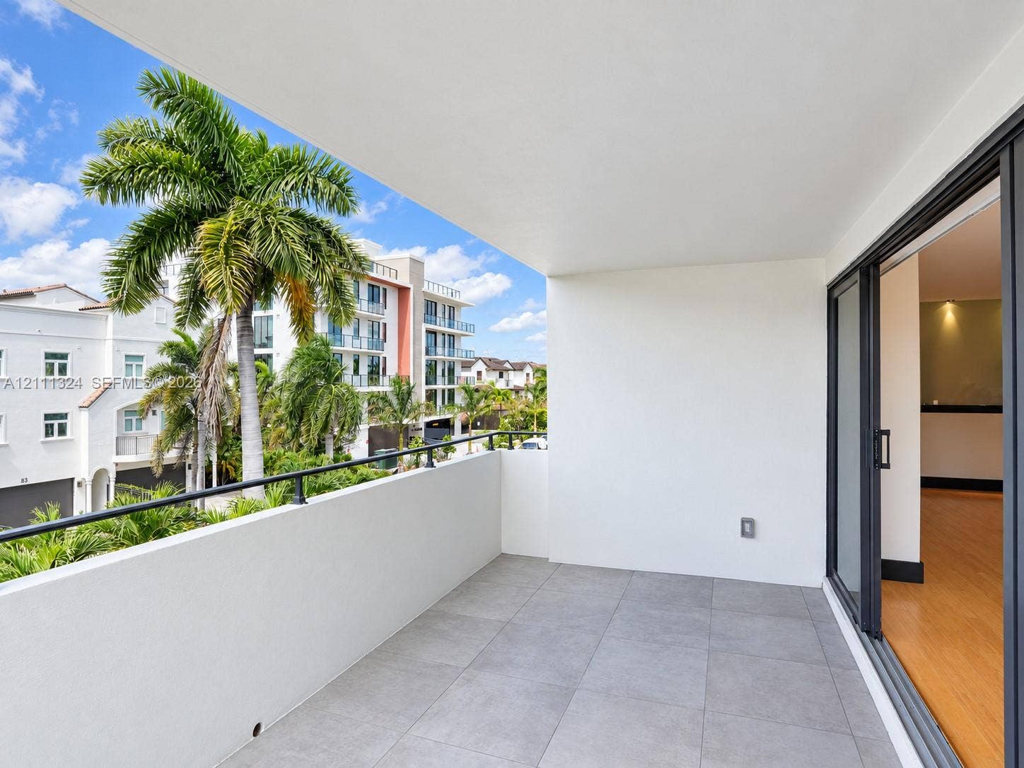 Covered balcony featuring oversized gray tile flooring, a metal railing, and sliding glass door access