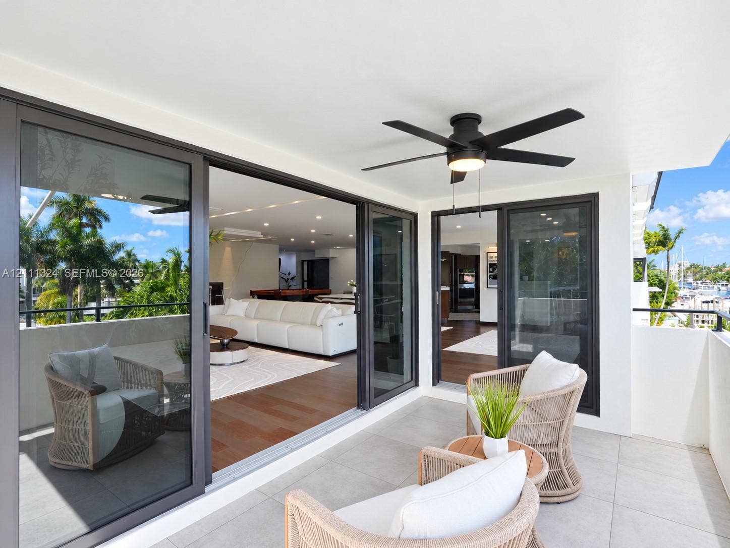Covered balcony featuring oversized porcelain tile flooring, black-framed sliding glass doors, and an integrated LED ceiling fan