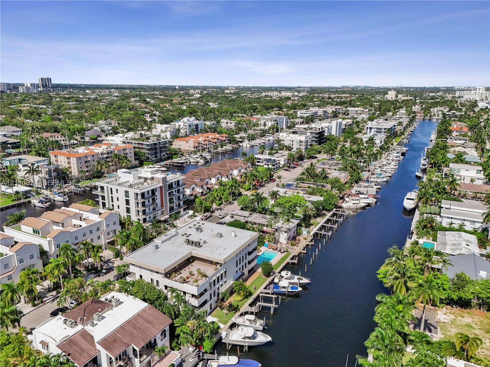 Aerial perspective of a waterfront residential district featuring private boat slips, deep-water canal access, multi-story masonry structures, and lush tropical landscaping