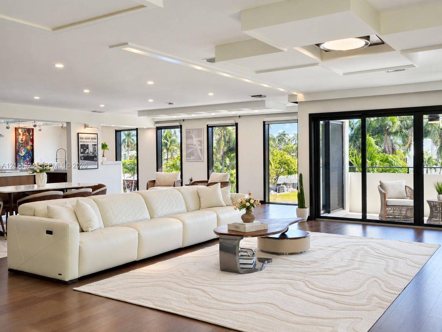 Open-concept living space featuring wood-finish flooring, custom tray ceiling with recessed lighting, and expansive floor-to-ceiling sliding glass doors