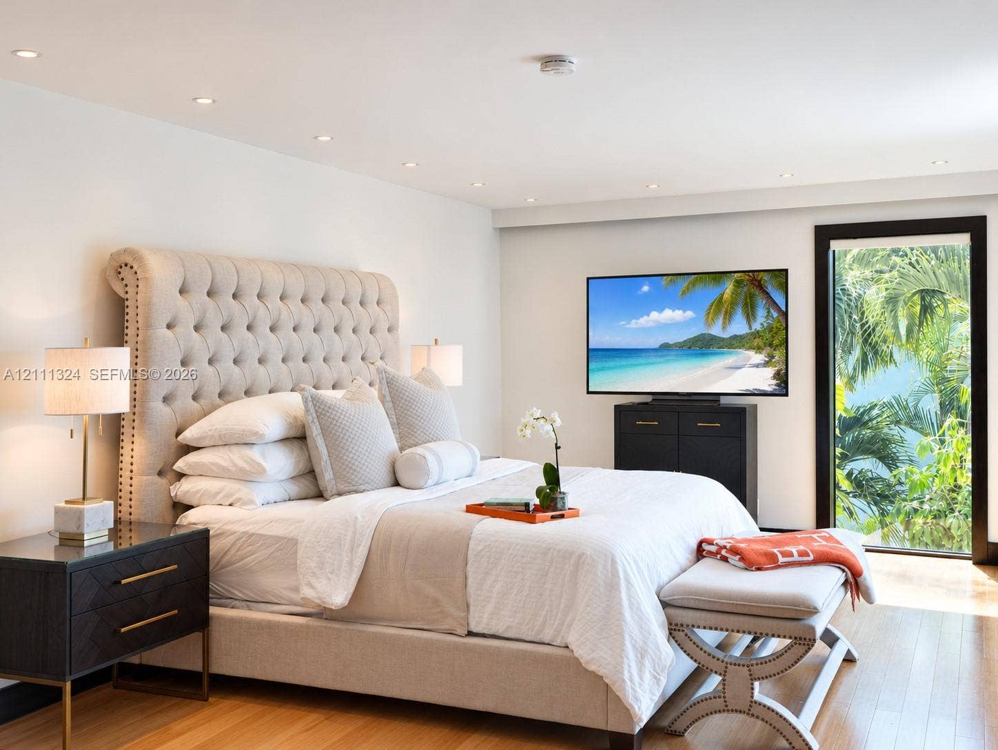Recessed lighting, wood-finish flooring, and a glass-paneled door with dark trim framing exterior foliage