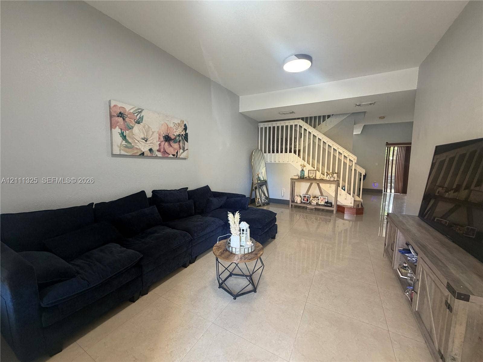 18172 SW 108th Path, Miami, Miami, FL 33157 Open-concept interior featuring large-format tile flooring, a painted wooden staircase with balustrades, and a recessed ceiling lighting fixture