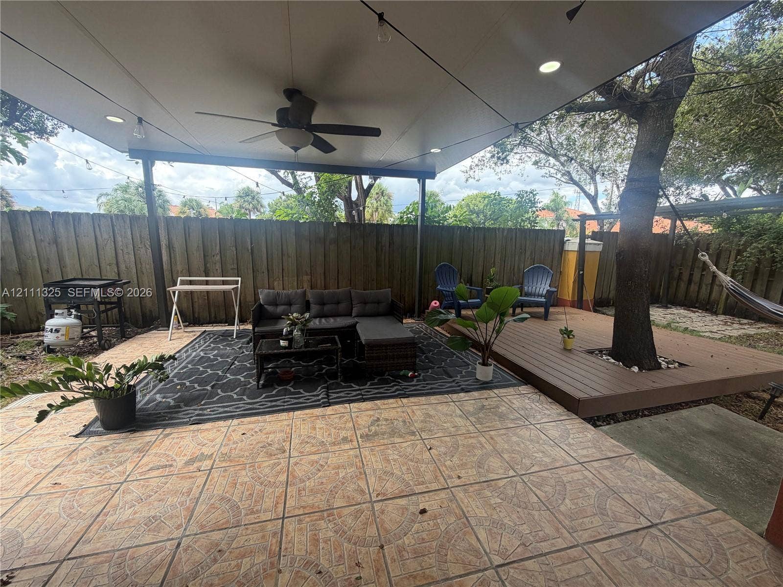 18172 SW 108th Path, Miami, Miami, FL 33157 Covered patio featuring patterned tile flooring, recessed lighting, and a ceiling fan, complemented by an elevated wood-finish deck surrounding a mature tree
