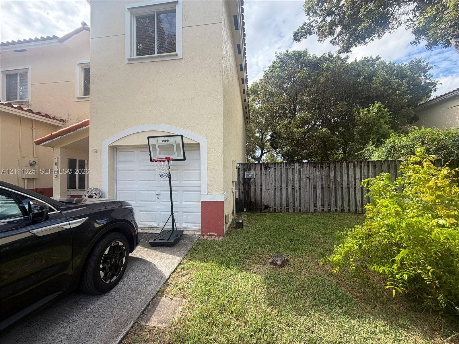18172 SW 108th Path, Miami, Miami, FL 33157 Stucco exterior with arched garage entry, concrete driveway, and wooden privacy fencing