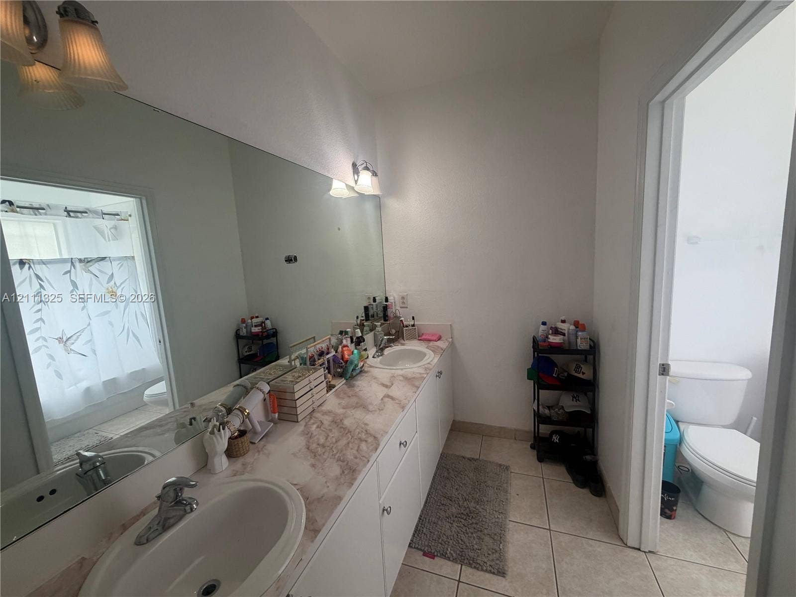 18172 SW 108th Path, Miami, Miami, FL 33157 Full-width vanity featuring dual oval drop-in sinks, stone-patterned countertop, white cabinetry, expansive wall-mounted mirror, and tile flooring