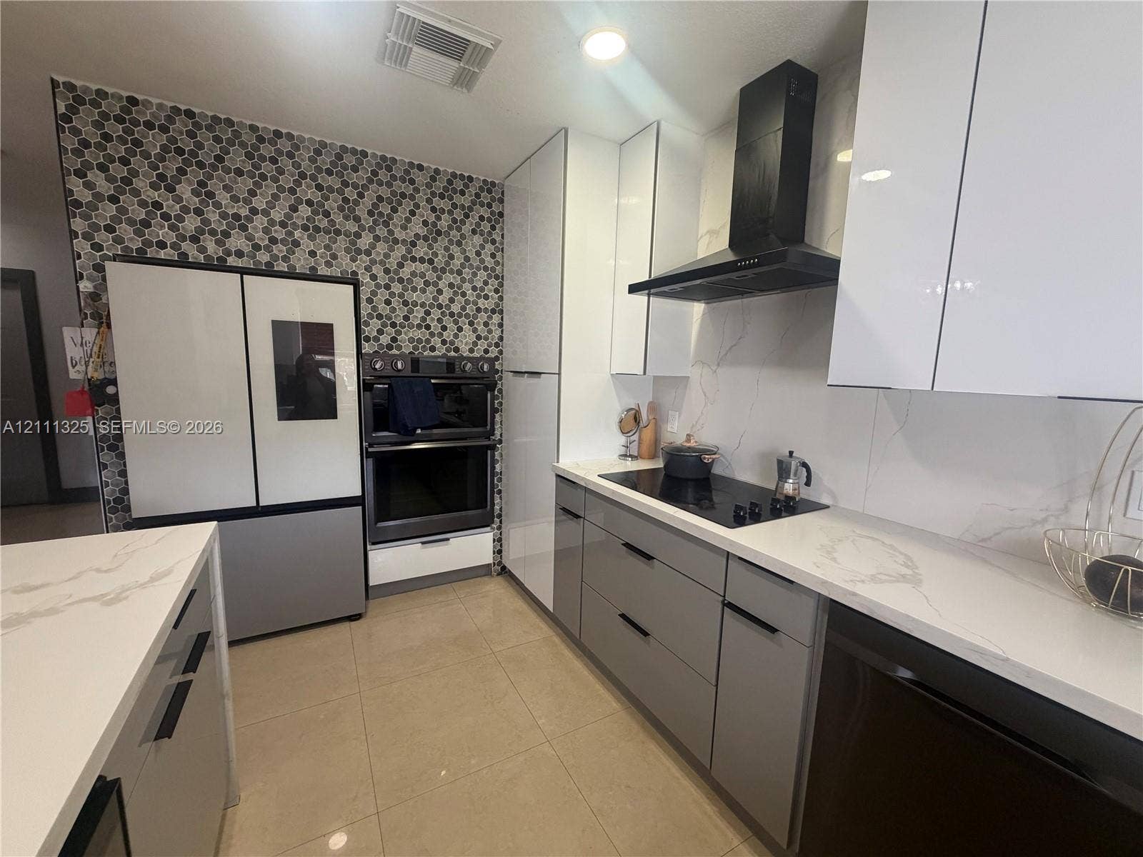 18172 SW 108th Path, Miami, Miami, FL 33157 Modern kitchen featuring high-gloss cabinetry, stone-finish countertops with a full-height backsplash, hexagonal mosaic wall tiling, and a built-in double oven with a matching overhead vent hood
