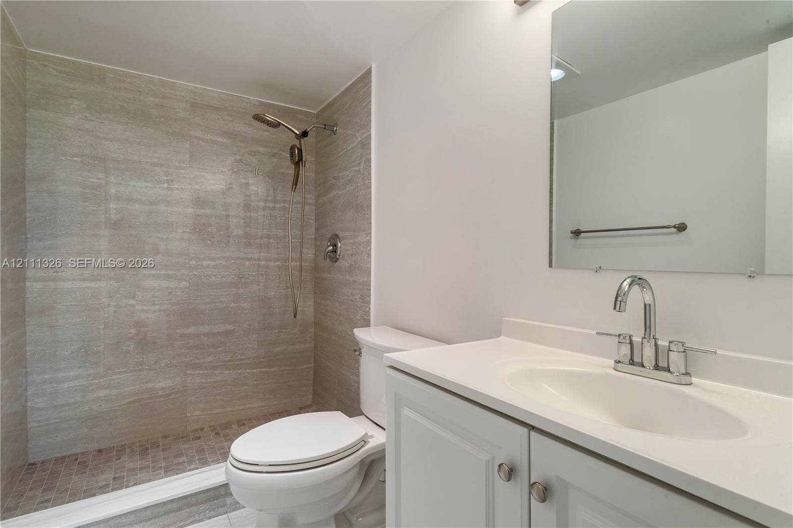 4801 Esedra Court, #207, Lake Worth, FL 33467 Walk-in shower with tile surround, white vanity with integrated sink, and wall-mounted mirror.