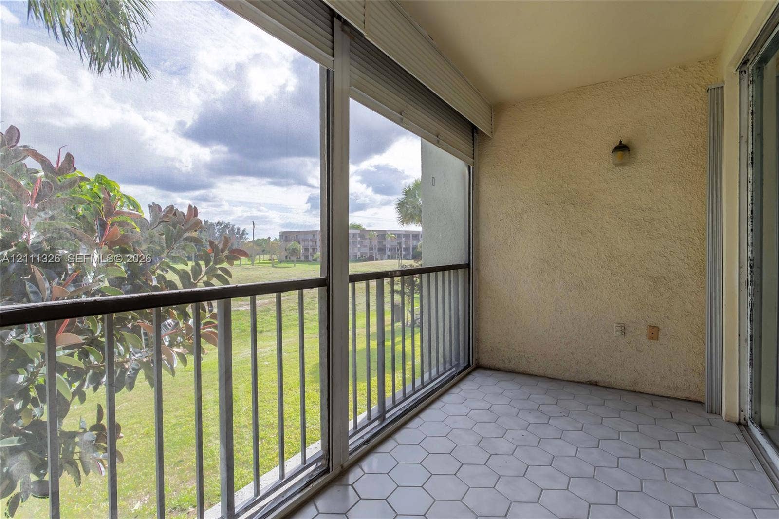 4801 Esedra Court, #207, Lake Worth, FL 33467 Screened-in balcony featuring hexagonal tile flooring, metal railings, textured wall finish and beautiful view.