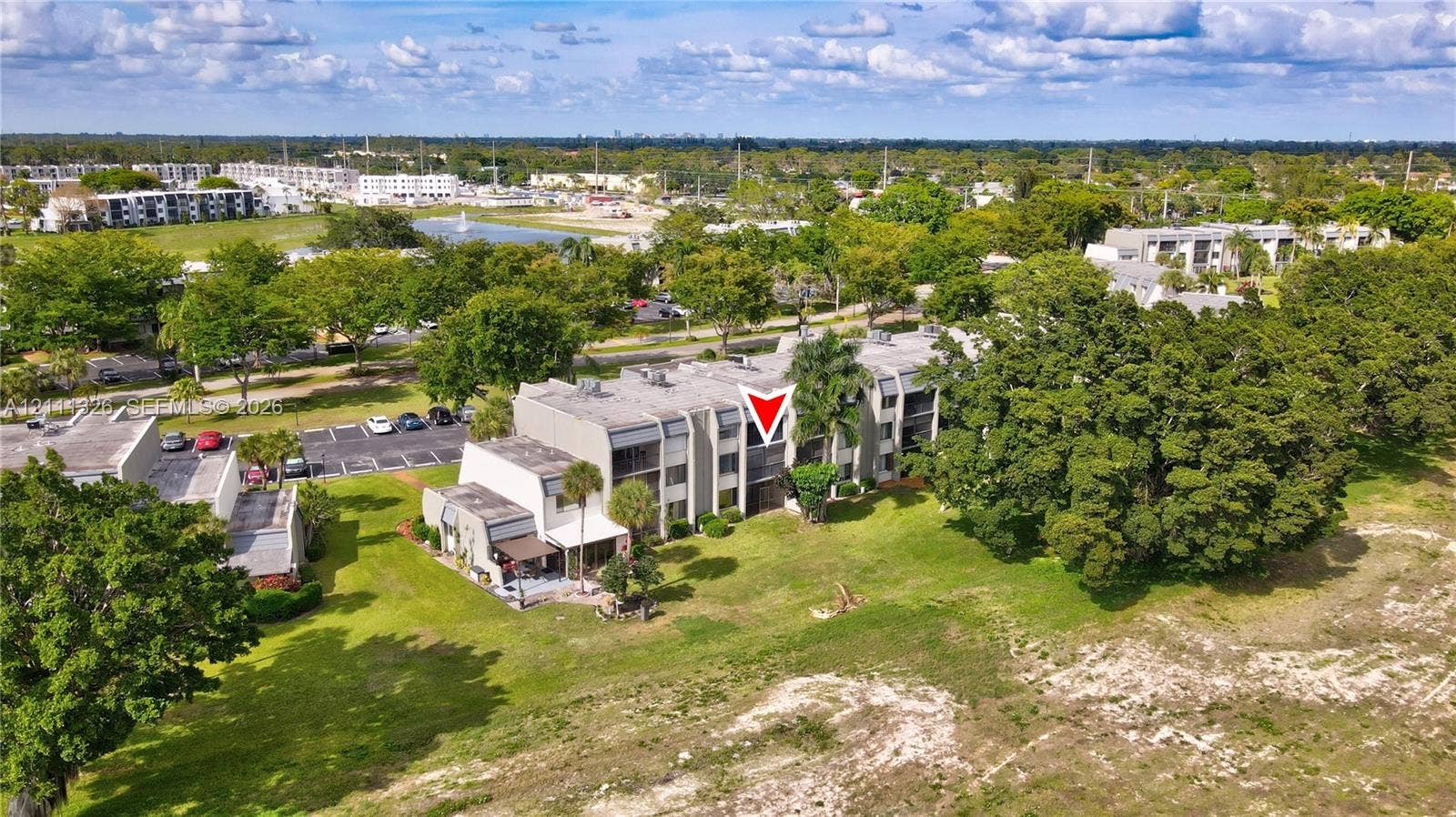 4801 Esedra Court, #207, Lake Worth, FL 33467 Multi-story residential building featuring concrete construction, flat roofline, private balconies, and surrounding green space with mature trees