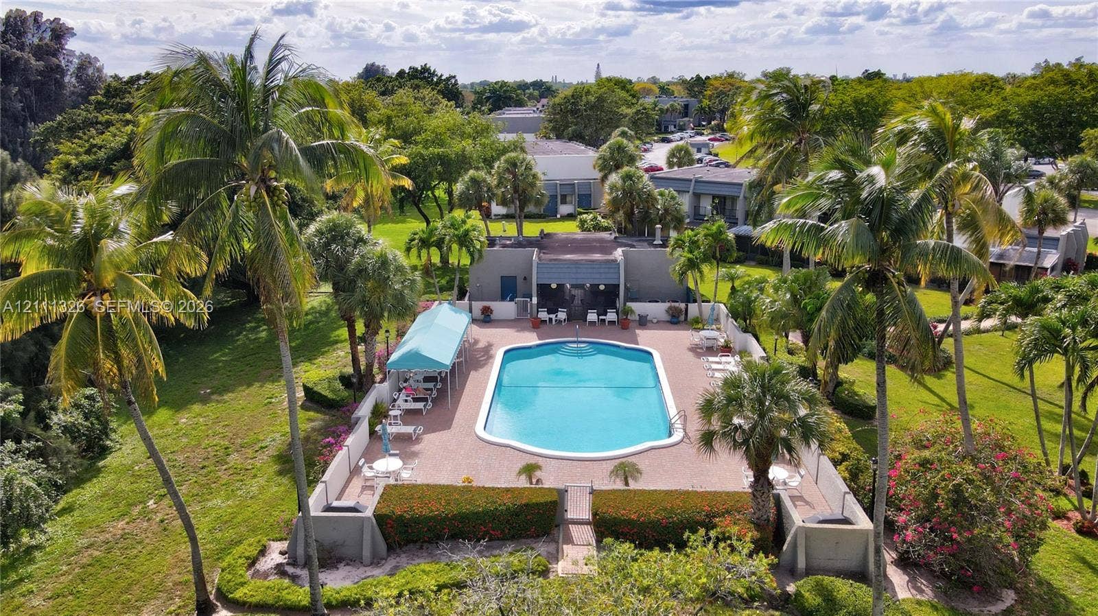 4801 Esedra Court, #207, Lake Worth, FL 33467 Outdoor community swimming pool with surrounding paver deck, covered patio area, and perimeter wall enclosure situated within a landscaped setting of mature trees.