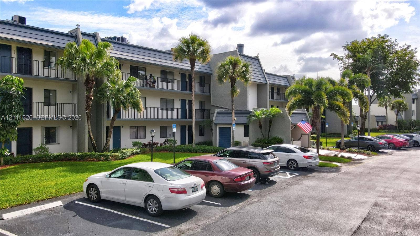 4801 Esedra Court, #207, Lake Worth, FL 33467 Multi-level exterior featuring a grey facade, tiered balcony railings and plentiful parking spaces.