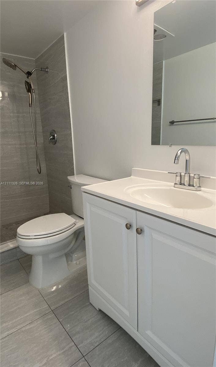 4801 Esedra Court, #207, Lake Worth, FL 33467 Bathroom featuring a white vanity cabinet with a solid surface countertop, an integrated sink basin, a walk-in shower with horizontal-patterned wall tile, and large-format floor tile