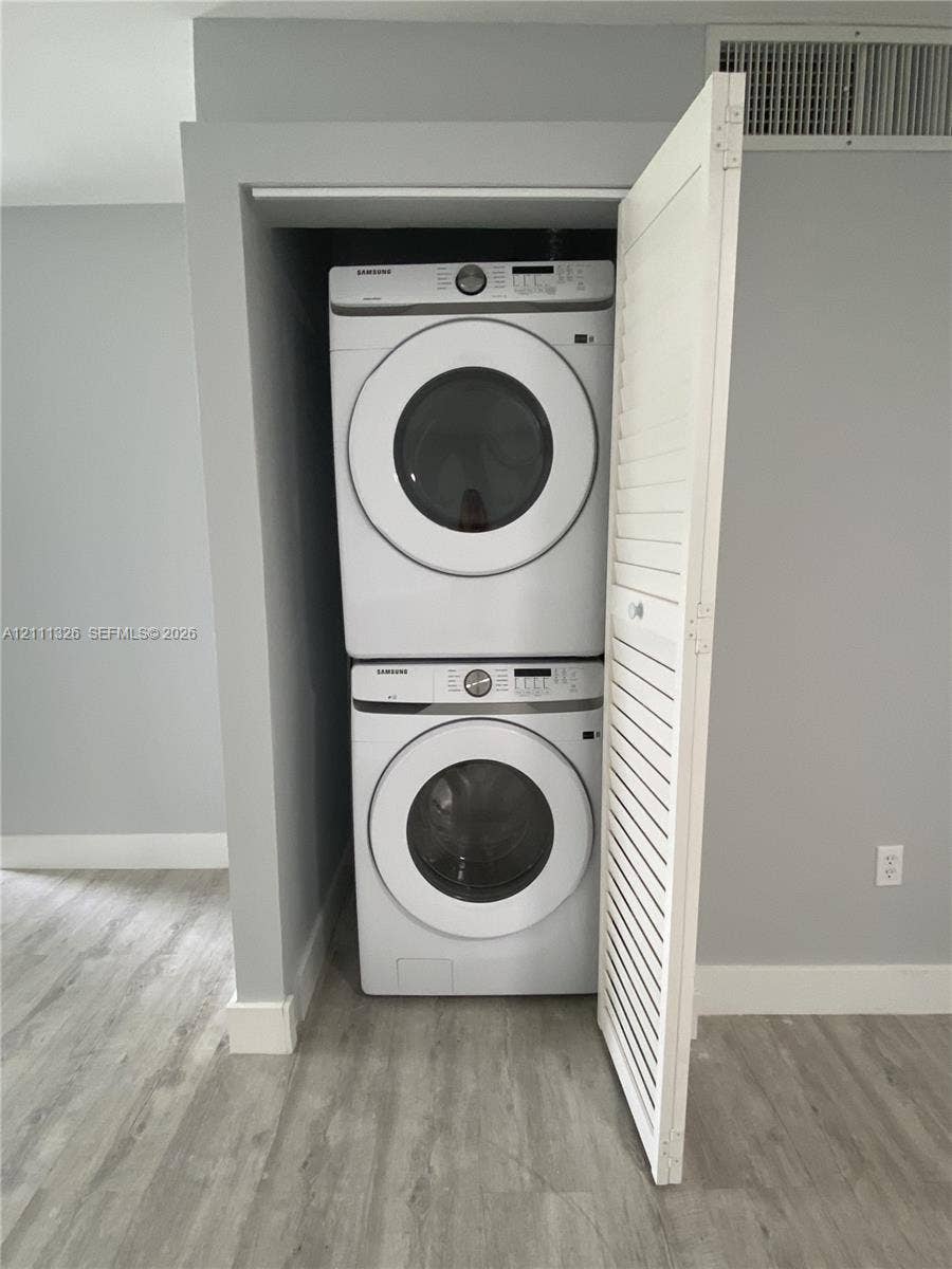 4801 Esedra Court, #207, Lake Worth, FL 33467 Dedicated laundry alcove featuring stacked, full sized high-capacity front-load washer and dryer units enclosed by a white louvered door