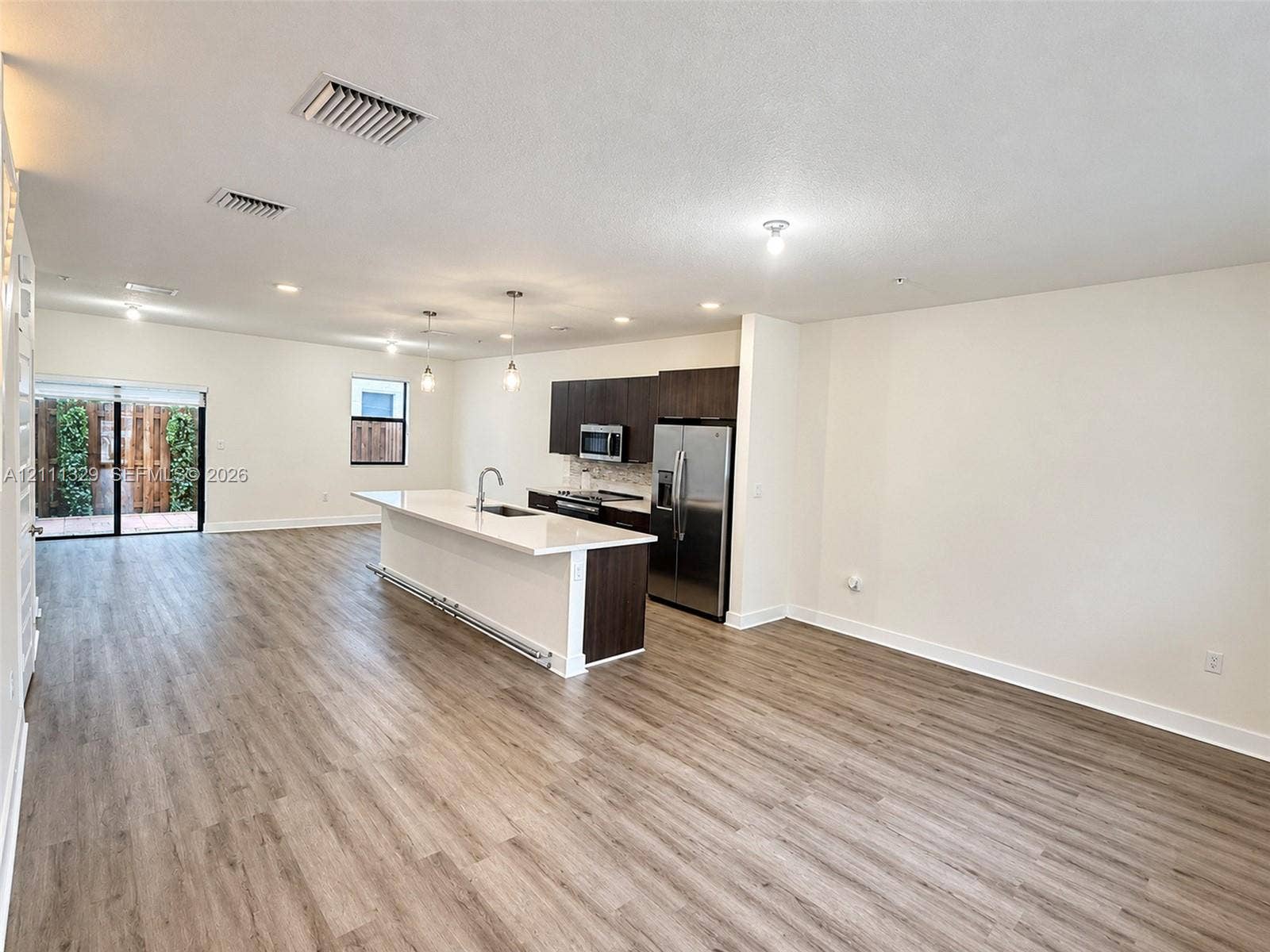 10443 NW 82nd Street, #6, Doral, Doral, FL 33178 Open-concept kitchen featuring dark wood-finish cabinetry, white stone countertops, an oversized center island, stainless steel appliances, and wood-finish flooring