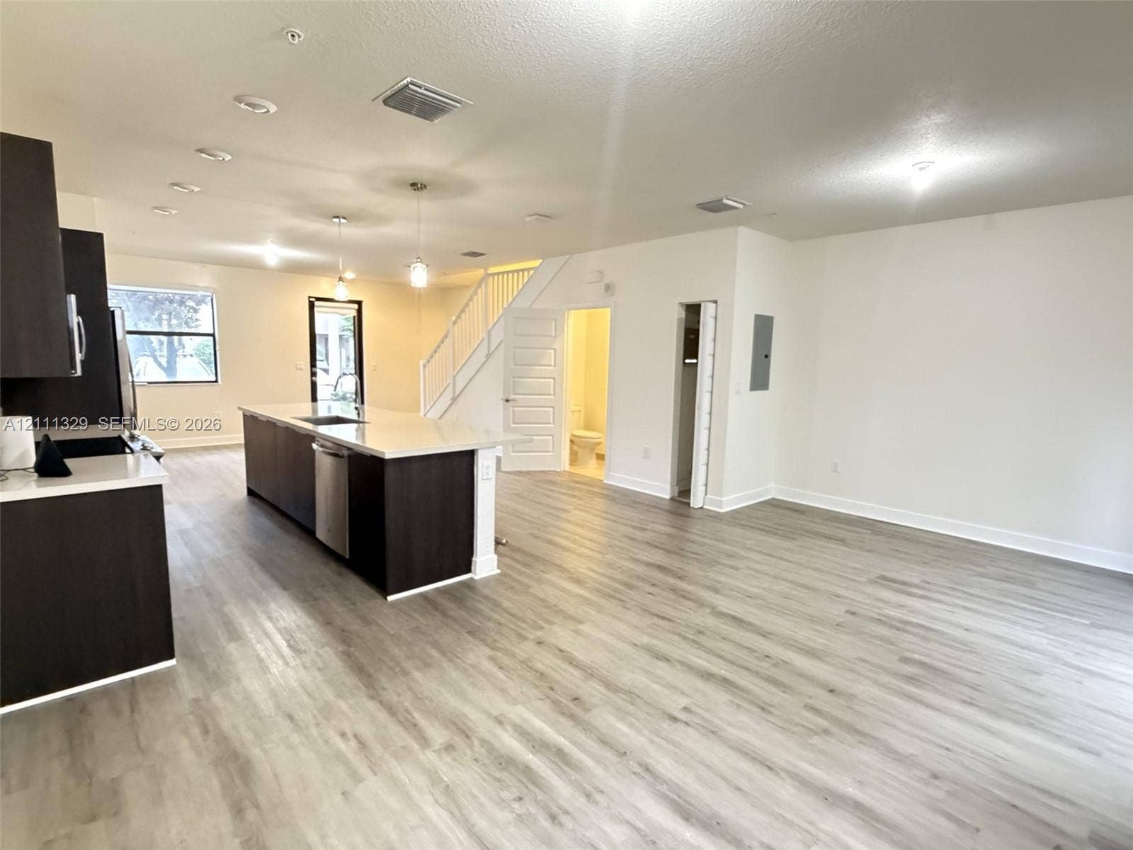 10443 NW 82nd Street, #6, Doral, Doral, FL 33178 Open-concept floor plan featuring wood-finish flooring, a kitchen island with stone-surface countertops, dark-tone cabinetry, and recessed lighting