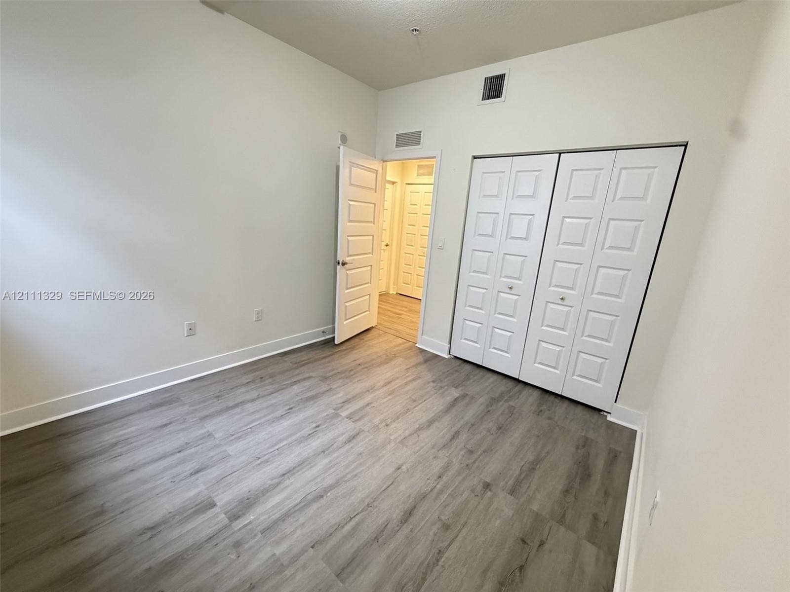 10443 NW 82nd Street, #6, Doral, Doral, FL 33178 Room featuring wood-finish flooring, high ceilings, white panel interior doors, and a double-door closet with square-panel detailing