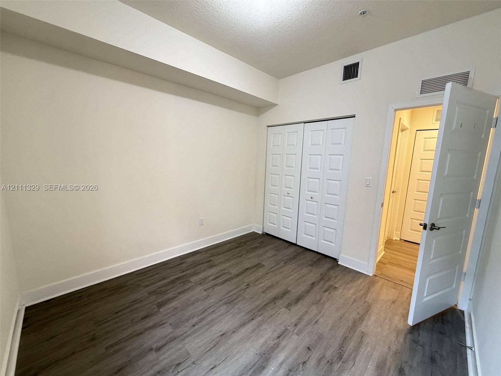 10443 NW 82nd Street, #6, Doral, Doral, FL 33178 Room featuring wood-finish flooring, recessed ceiling design, and dual-panel closet doors