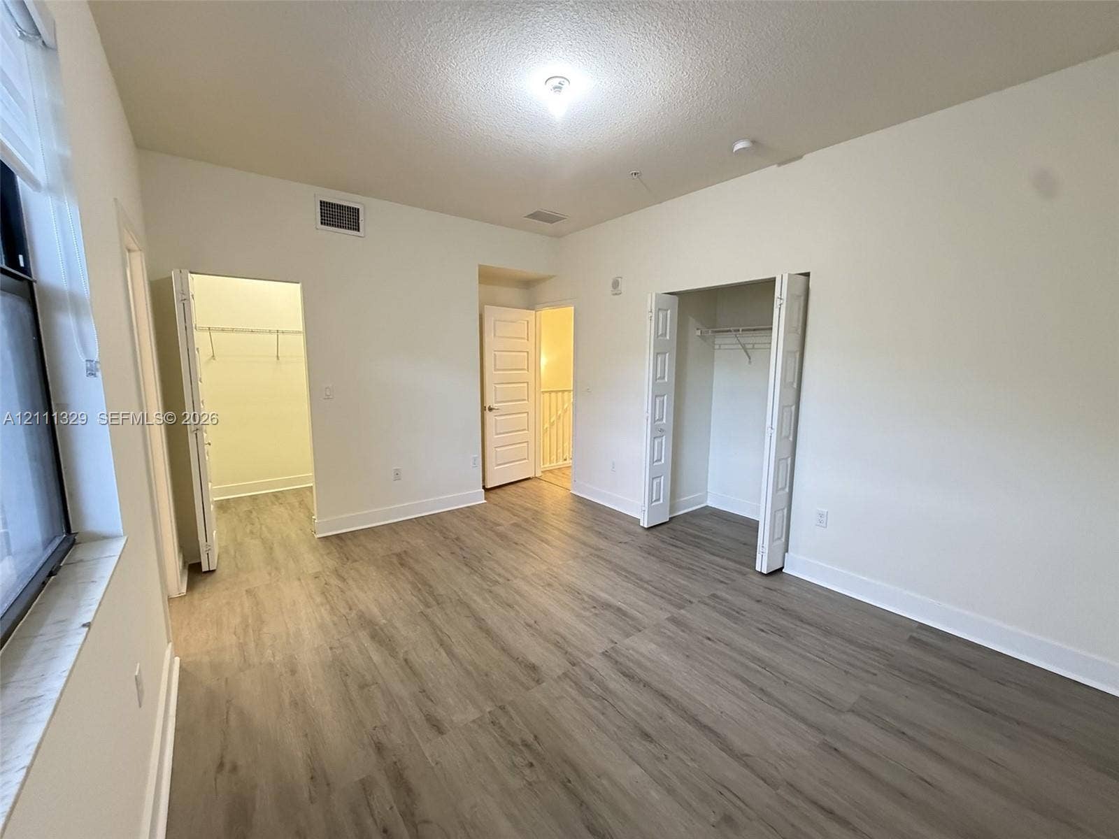 10443 NW 82nd Street, #6, Doral, Doral, FL 33178 Room with neutral wall finish, wood-finish flooring, two bi-fold door closets, and a multi-panel interior door