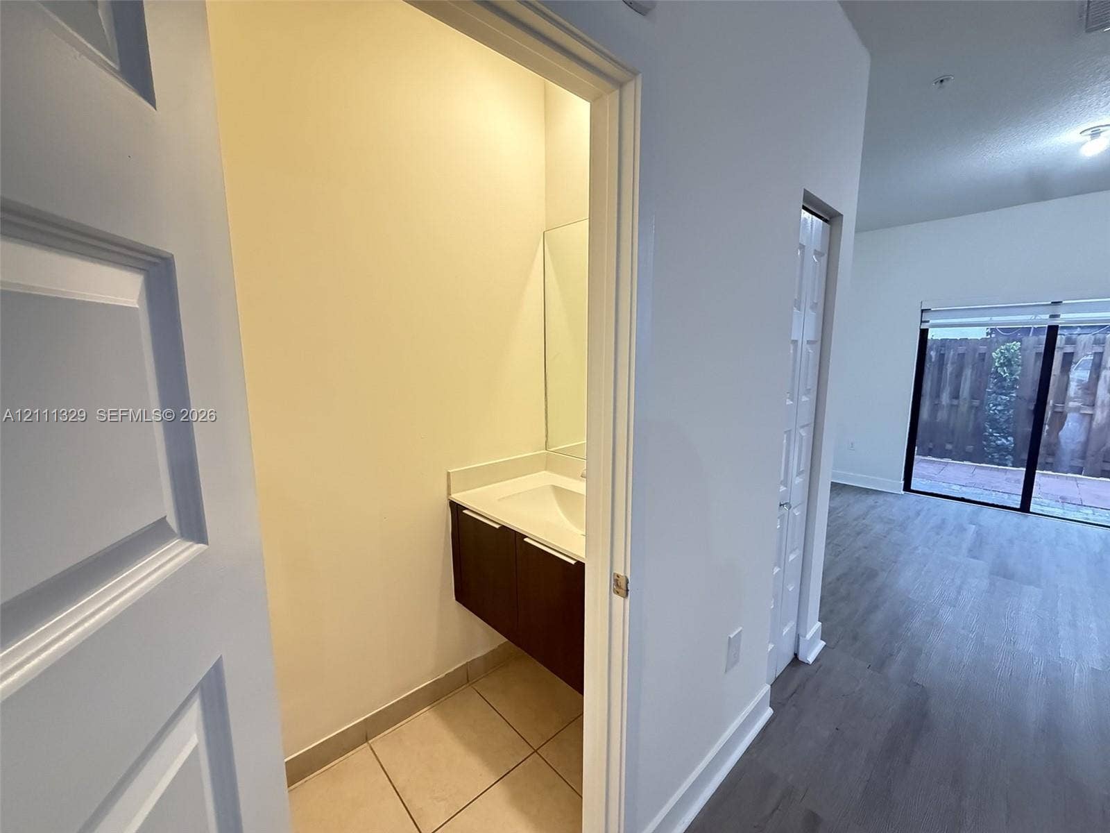 10443 NW 82nd Street, #6, Doral, Doral, FL 33178 Modern floating vanity with a rectangular sink, white countertop, and dark-finish cabinetry, complemented by tile flooring and a wall-mounted mirror