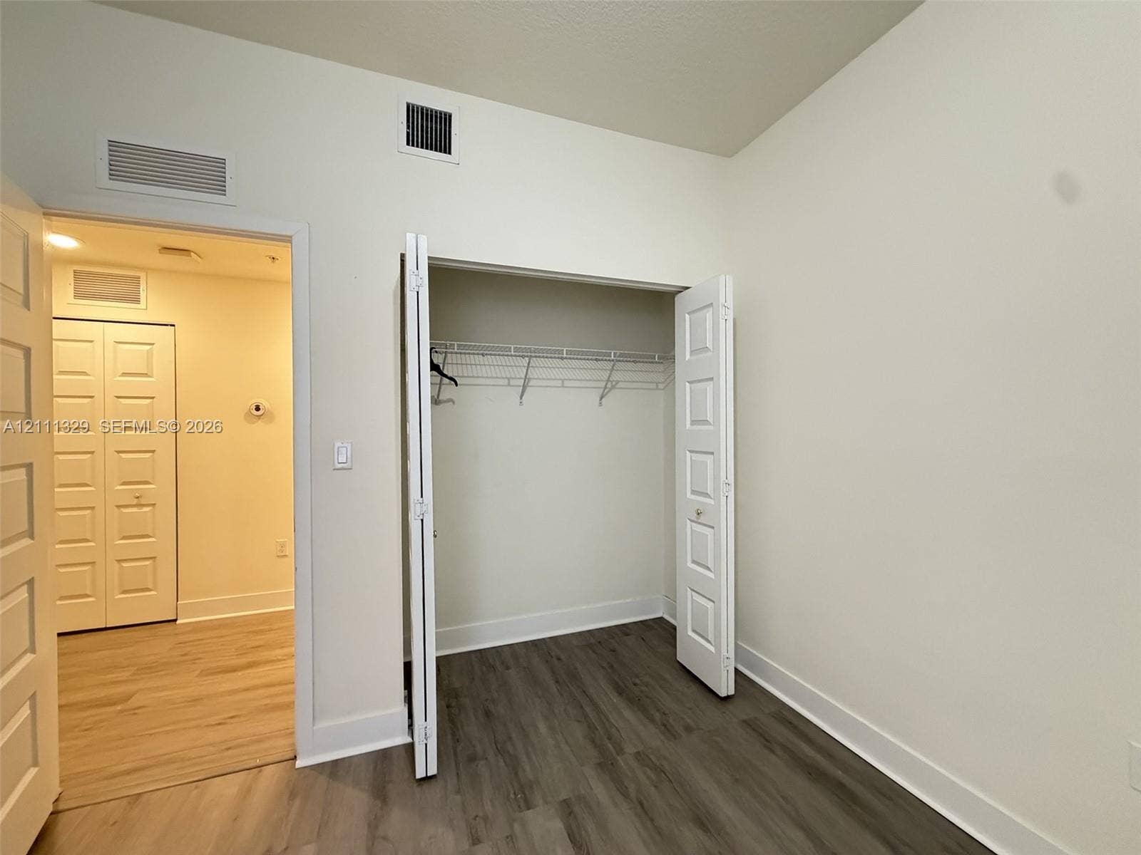 10443 NW 82nd Street, #6, Doral, Doral, FL 33178 Interior space featuring wood-finish flooring, white five-panel interior doors, and a reach-in closet with integrated wire shelving