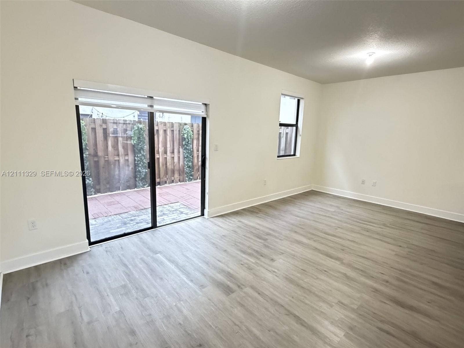 10443 NW 82nd Street, #6, Doral, Doral, FL 33178 Interior space featuring light-toned wood-finish flooring, sliding glass patio doors, neutral wall palette, and a rectangular window