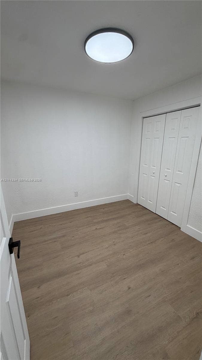 3314 NW 8th, #1, Miami, Miami, FL 33131 Interior space featuring wood-finish flooring, white walls, double-door closet, and flush-mount circular lighting fixture
