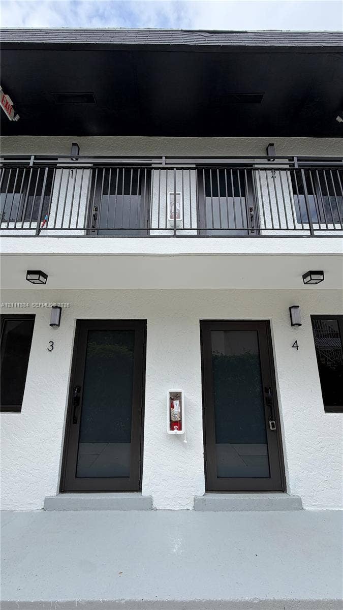 3314 NW 8th, #1, Miami, Miami, FL 33131 Two-story exterior featuring a stucco facade, private balcony with metal railings, and full-lite glass entry doors