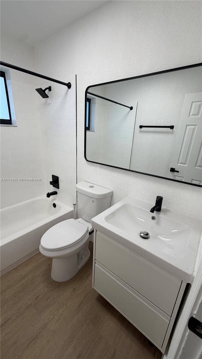 3314 NW 8th, #1, Miami, Miami, FL 33131 Bathroom featuring a vanity with integrated sink, black matte hardware, framed mirror, and wood-finish flooring