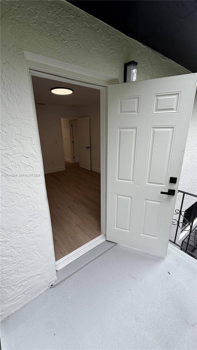 3314 NW 8th, #1, Miami, Miami, FL 33131 Six-panel entry door featuring a matte black electronic deadbolt and handle set, textured exterior wall finish, wood-finish flooring, and recessed circular ceiling lighting