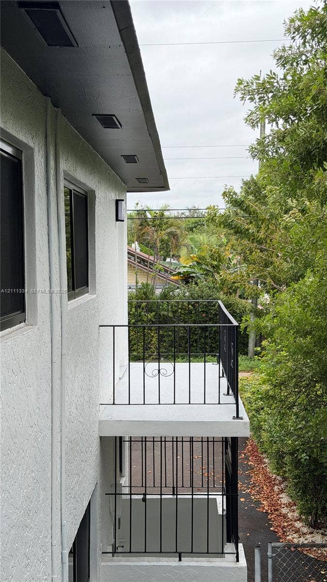 3314 NW 8th, #1, Miami, Miami, FL 33131 Stucco exterior featuring dual-level outdoor balconies with black metal railings, recessed soffit lighting, and window screens