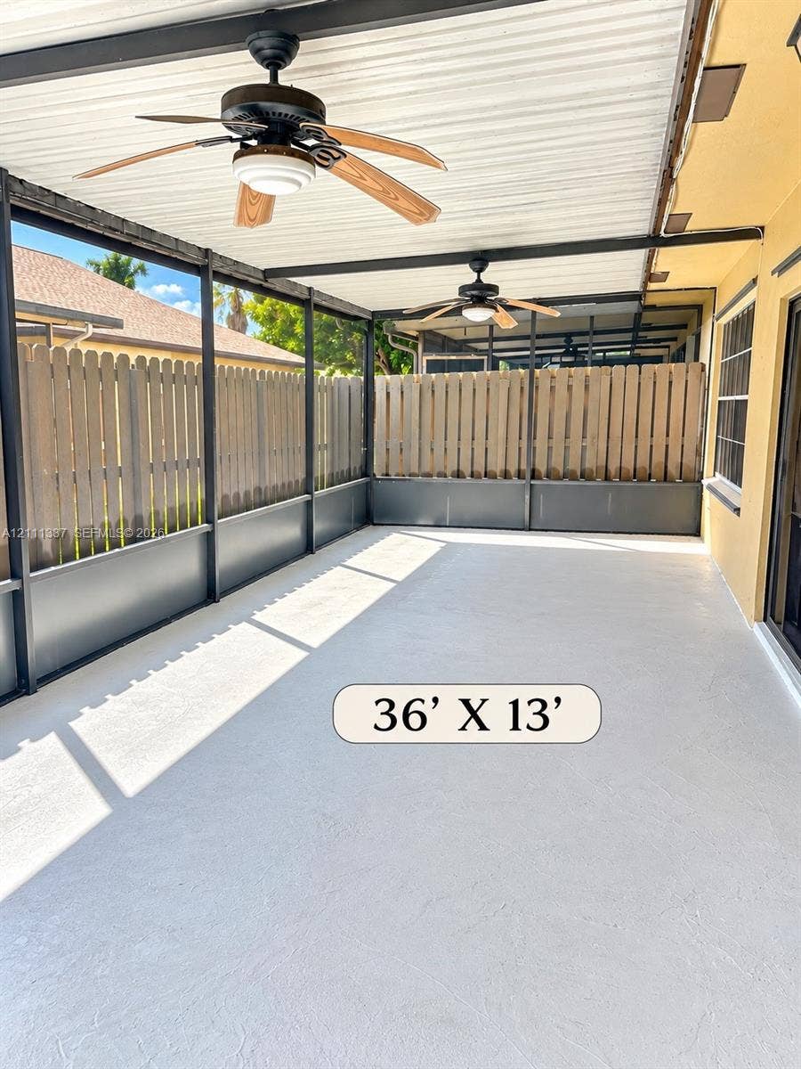 Screened-in patio measuring 36' by 13' featuring a concrete floor, two ceiling fans, and a wood-slat privacy fence