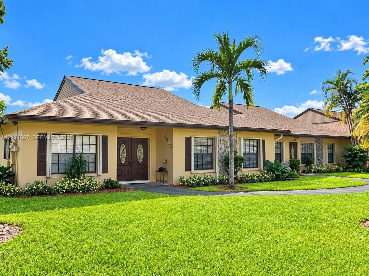 Single-story exterior featuring a hip roof, dual-entry doors with decorative glass inserts, stone masonry accents, and multi-pane windows with shutters