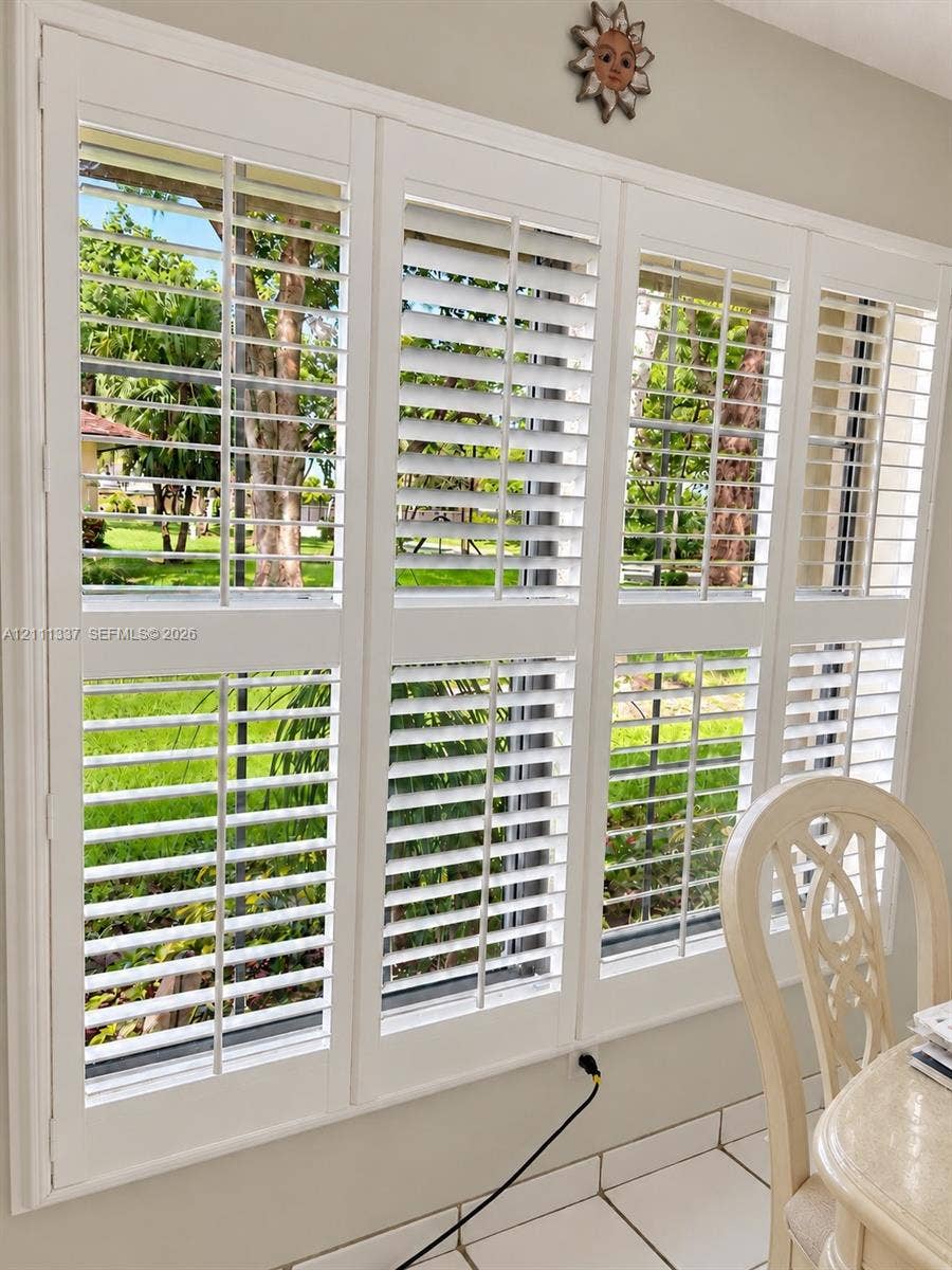 Large multi-panel window featuring white plantation shutters and light-toned ceramic tile flooring