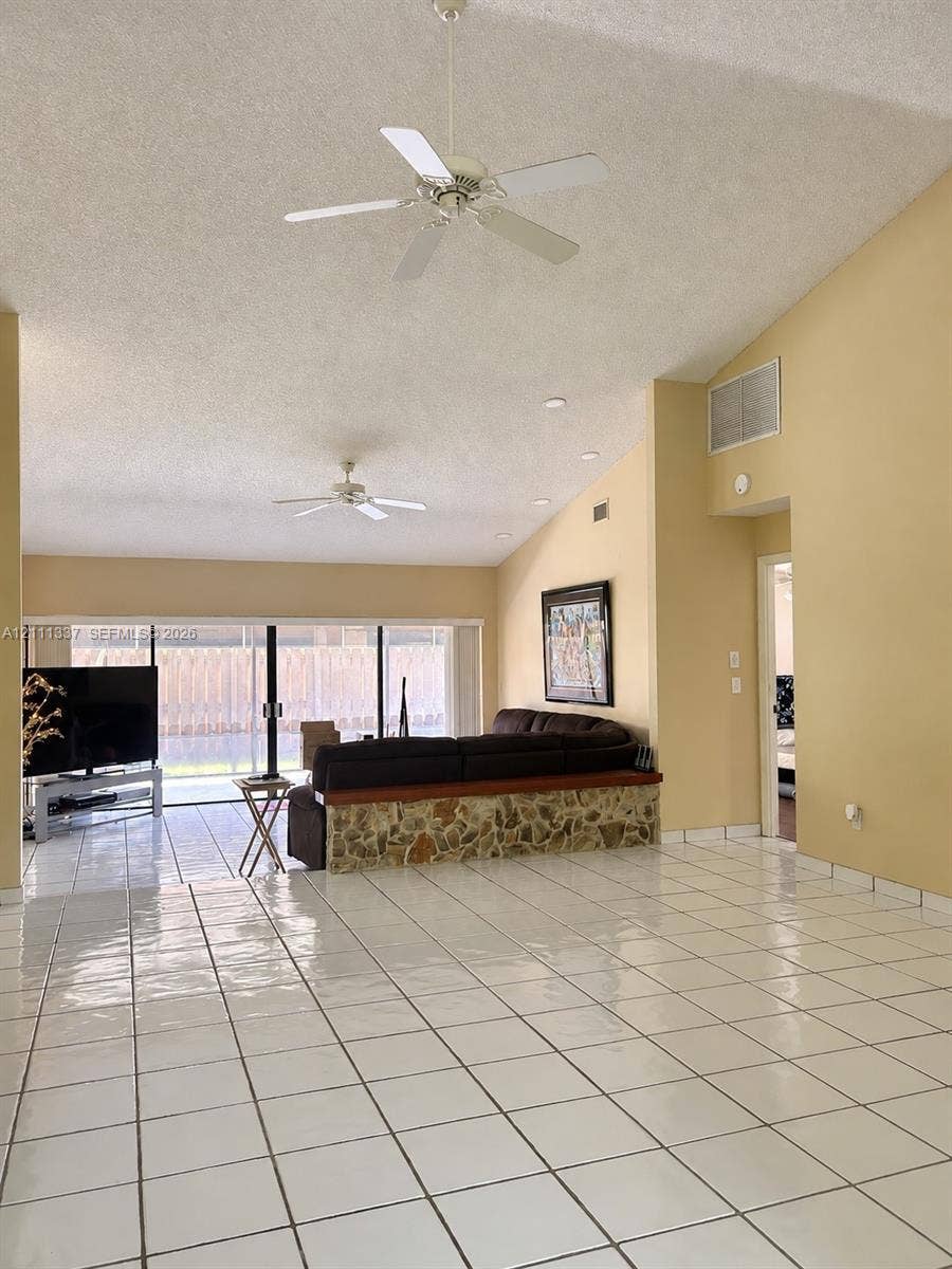 Vaulted ceilings, large-format tile flooring, dual ceiling fans, and sliding glass doors