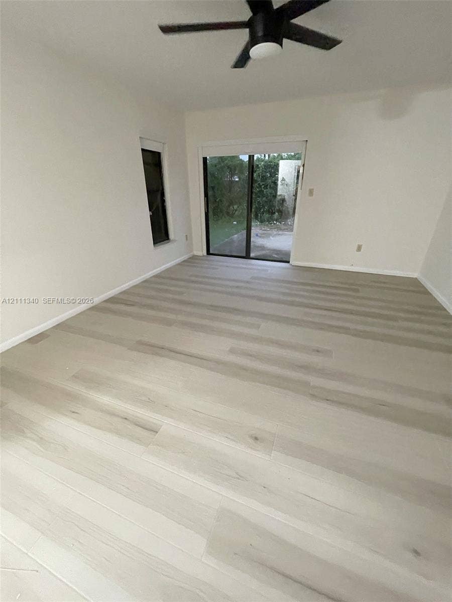 3330 SW 1st Street, Deerfield Beach, Deerfield Beach, FL 33442 Room featuring wood-finish flooring, a matte black ceiling fan, and sliding glass doors