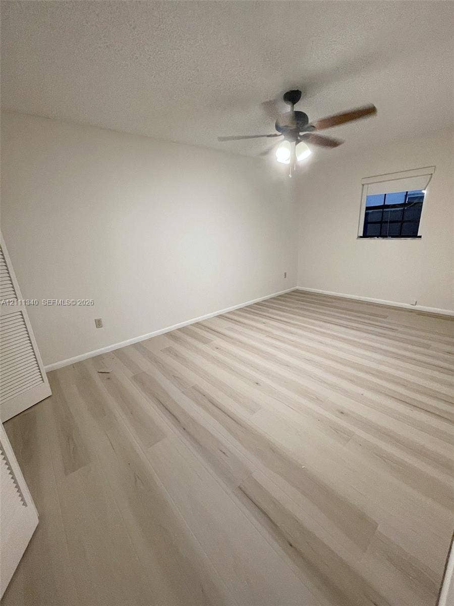 3330 SW 1st Street, Deerfield Beach, Deerfield Beach, FL 33442 Room featuring wood-finish flooring, a ceiling fan with integrated lighting, and a closet with louvered doors