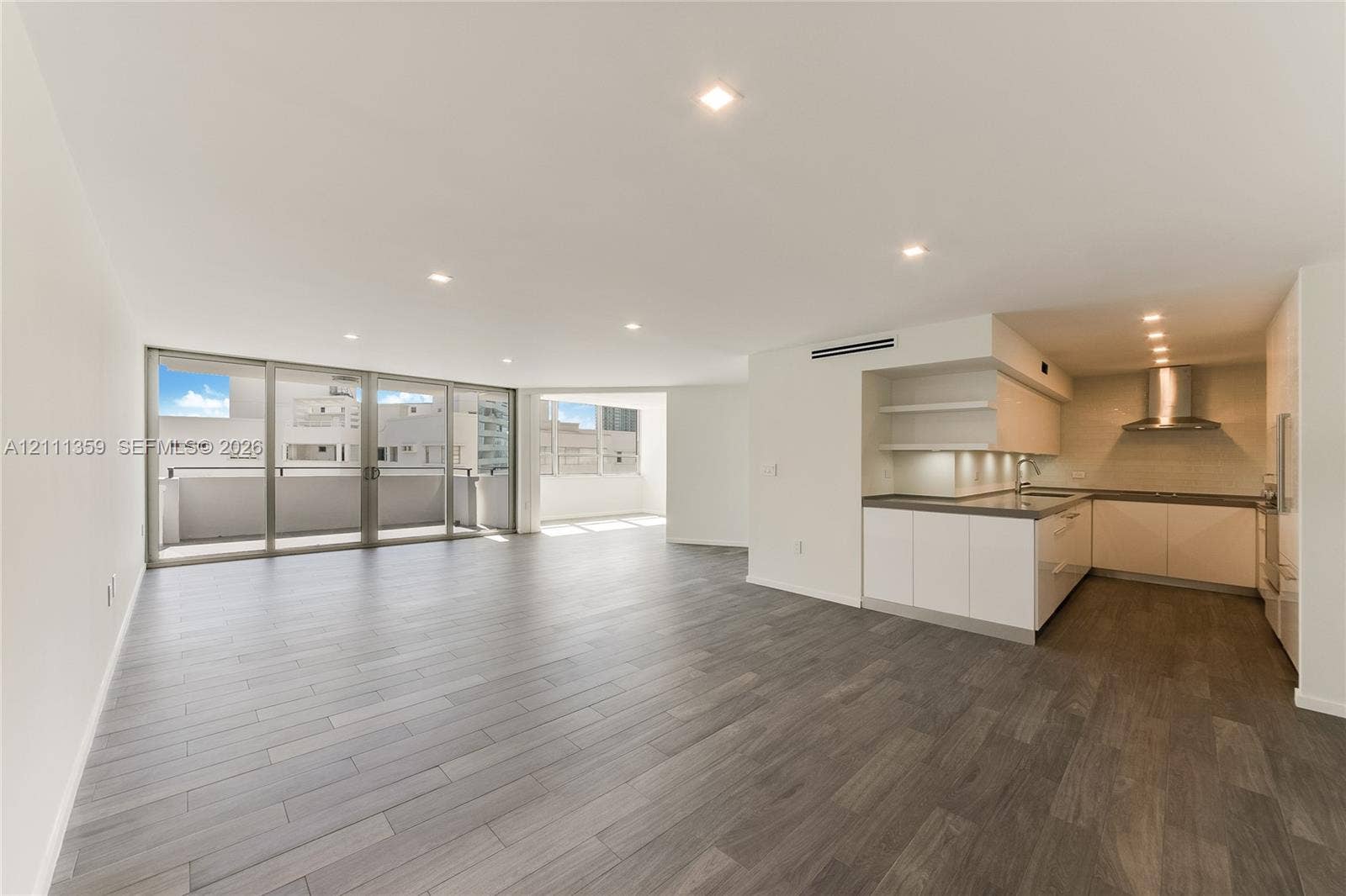 11 Island Avenue, #908, Miami Beach, Miami Beach, FL 33139 Open floor plan featuring wood-finish flooring, recessed lighting, floor-to-ceiling glass doors, and a kitchen equipped with cabinetry, stone-surface countertops, and a stainless steel range hood