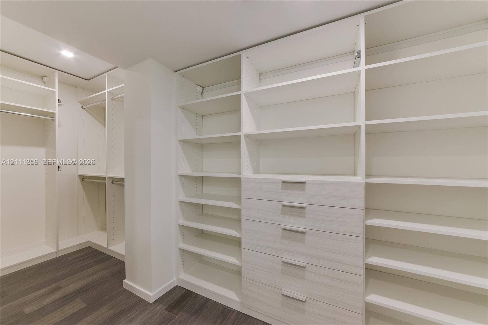11 Island Avenue, #908, Miami Beach, Miami Beach, FL 33139 Walk-in closet featuring extensive built-in shelving, integrated wood-finish cabinetry, a bank of five drawers with metallic hardware, and dark wood-finish flooring