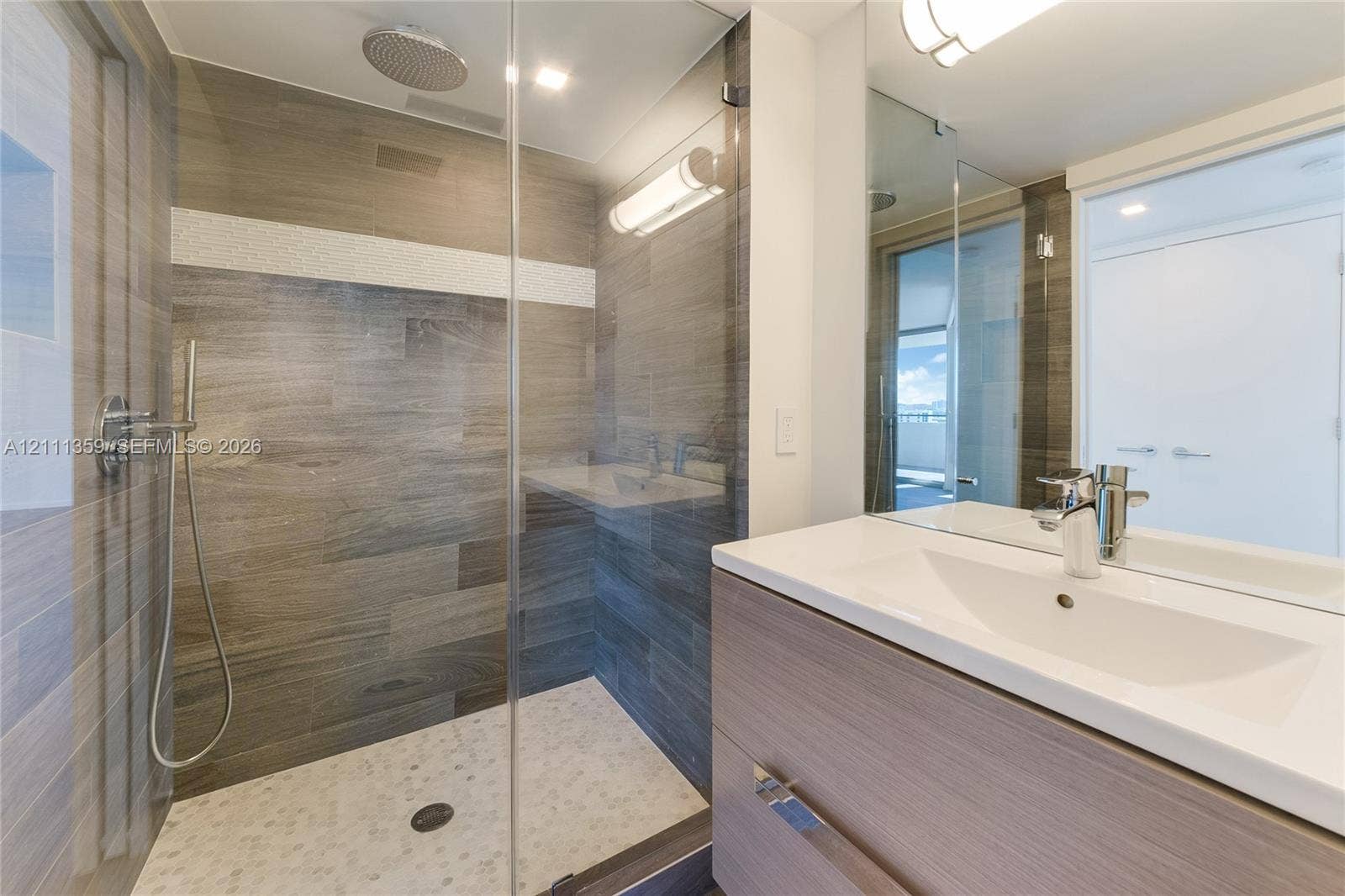 11 Island Avenue, #908, Miami Beach, Miami Beach, FL 33139 Bathroom featuring a glass-enclosed walk-in shower with stone tile flooring, wall-mounted rainfall showerhead, and handheld sprayer