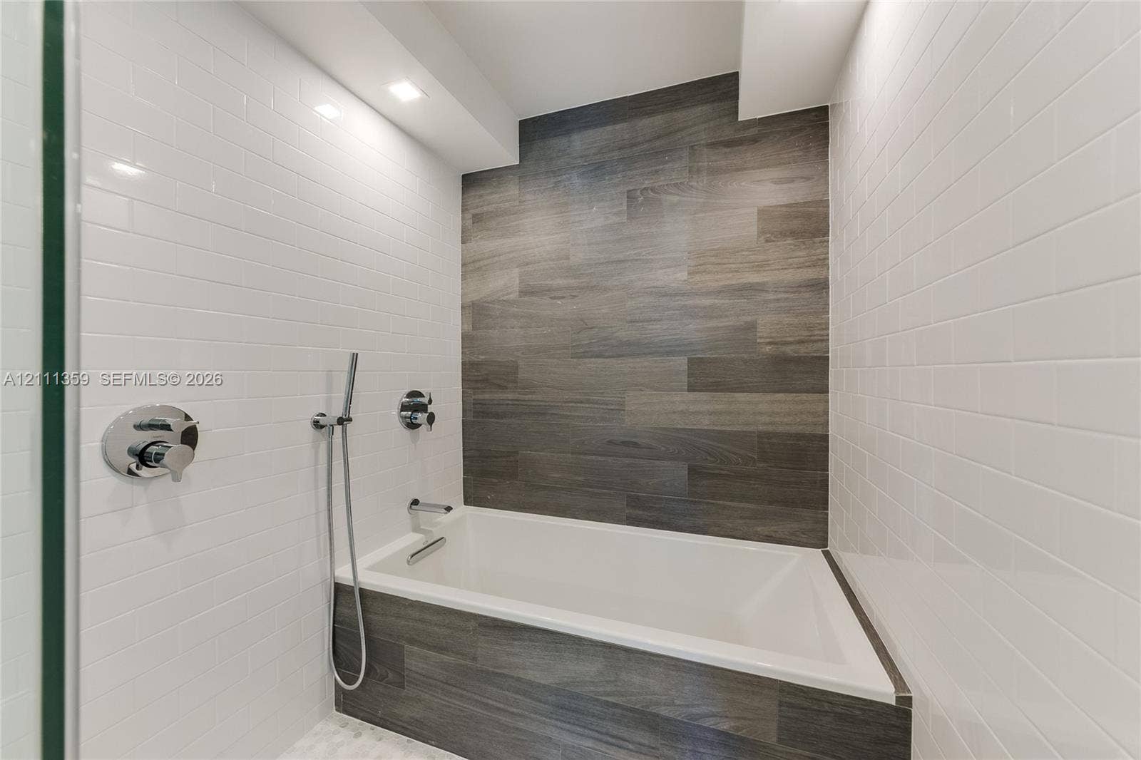 11 Island Avenue, #908, Miami Beach, Miami Beach, FL 33139 Built-in deep soaking tub featuring wood-finish tile surround, white subway tile walls, chrome shower fixtures, and recessed ceiling lighting