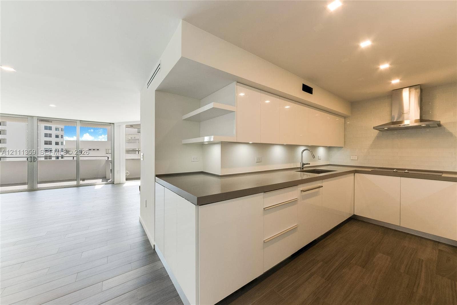 11 Island Avenue, #908, Miami Beach, Miami Beach, FL 33139 Modern kitchen featuring high-gloss white cabinetry, solid-surface countertops, stainless steel range hood, recessed lighting, and wood-finish flooring