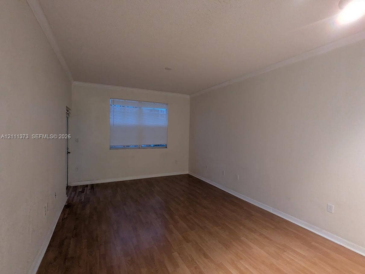 1801 N Flagler Drive, #912, West Palm Beach, West Palm Beach, FL 33401 Interior space featuring wood-finish flooring, neutral wall tones, crown molding, and a single window with integrated blinds